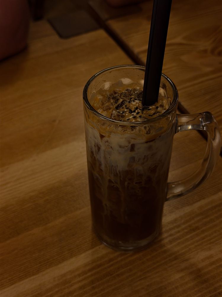 Highland Refresher Vietnamese iced coffee with creamy milk and sesame seeds in a glass mug at Umami Ku’damm.